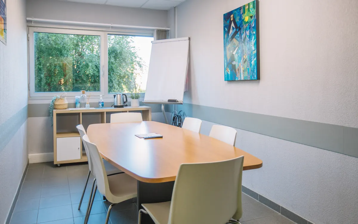 Salle de réunion de six personnes au Millénaire avec écran mural, paperboard et table de travail, prête pour une visioconférence depuis un ordinateur portable